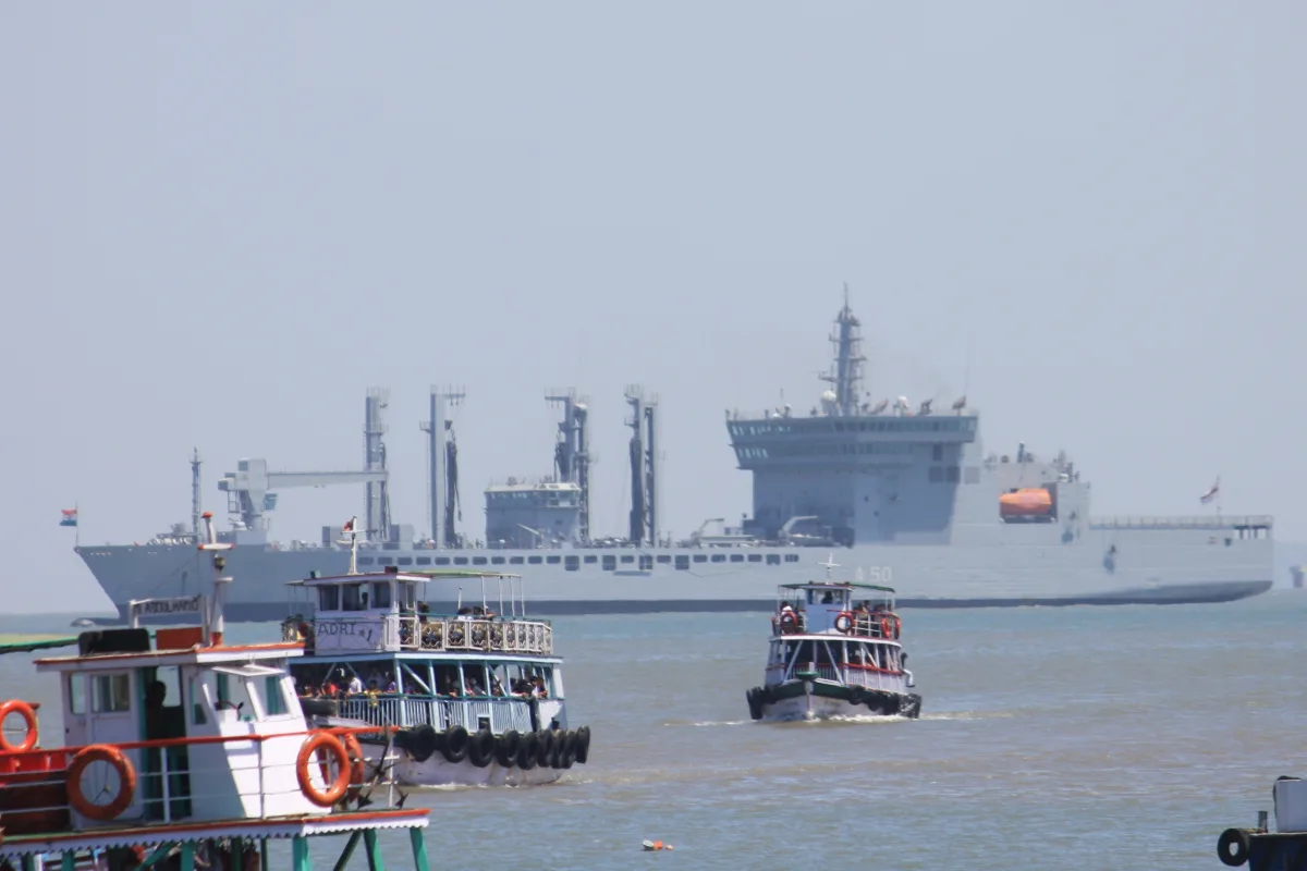The grey Indian Navy replenishment tanker INS Deepak off Mumbai with small boats in the foreground