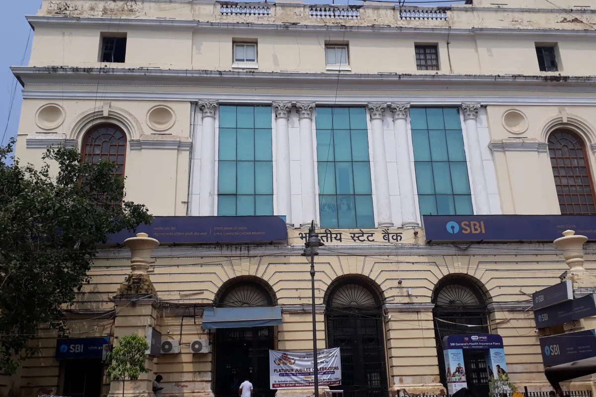 The cream-coloured heritage building of a State Bank of India branch in Chandni Chowk, Delhi, with blue SBI signboards