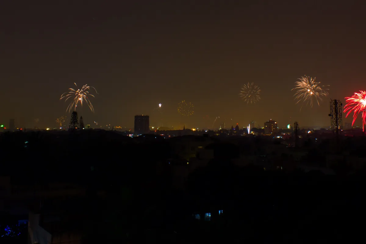 Fireworks bursting over a hazy city skyline at night