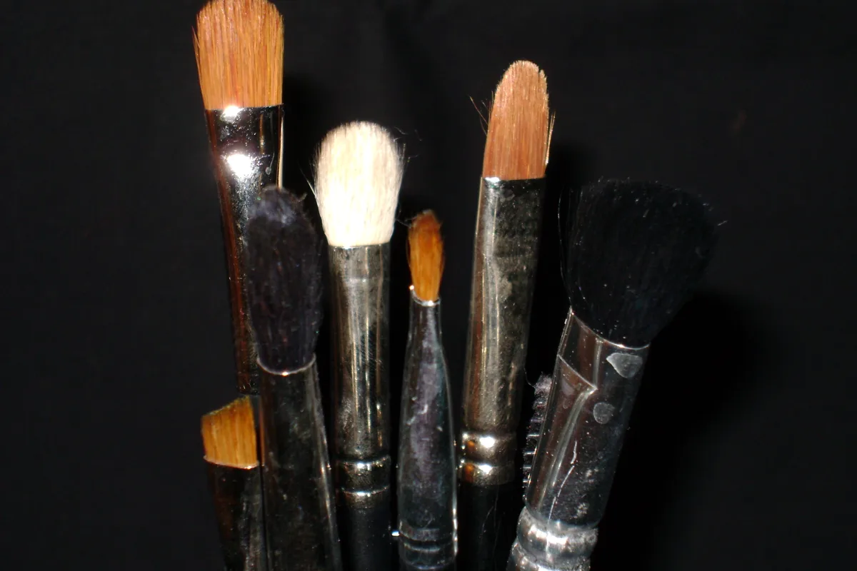 A cluster of make-up brushes of different shapes against a black background