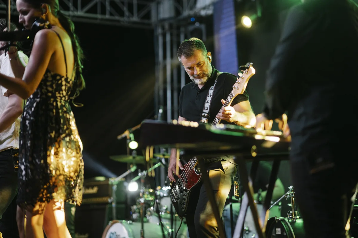 A singer and a guitarist performing on a stage lit with green and white lights at night