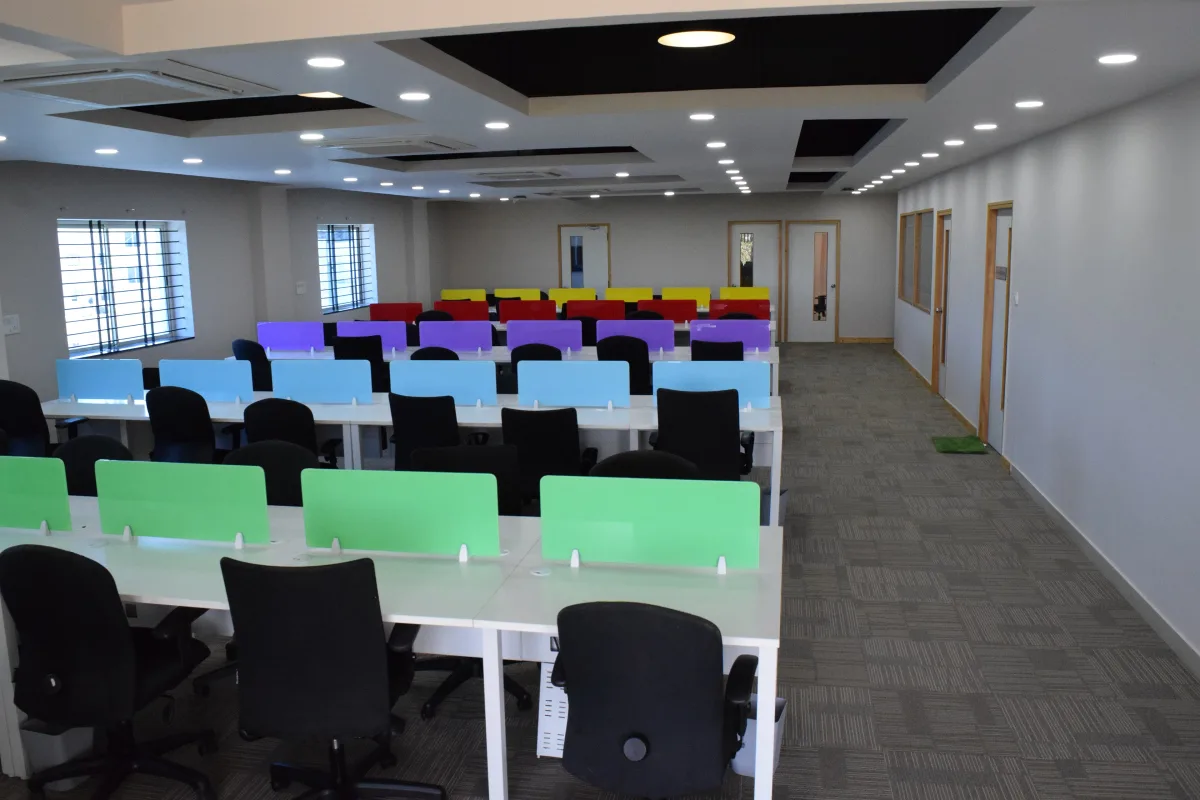 Rows of empty desks with coloured partitions in a coworking office