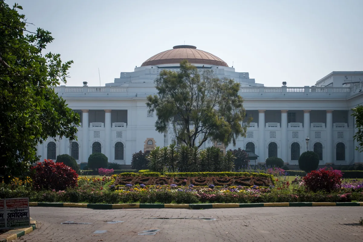 The white colonnaded West Bengal Legislative Assembly building in Kolkata with a dome and a flower garden in front