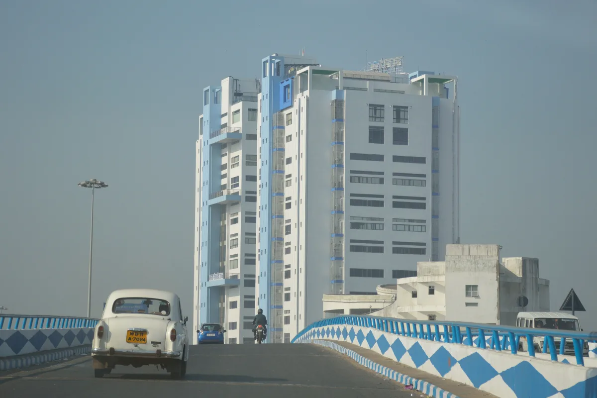The tall white and blue Nabanna building in Howrah seen from a bridge with a white car on the road